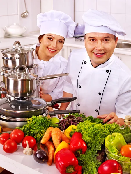 Muž a žena v klobouku šéfkuchaře vaření kuřecí. — Stock fotografie