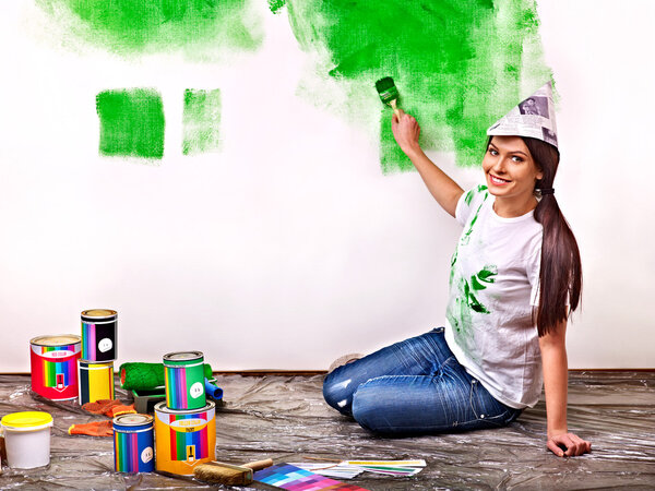 Woman paint wall at home.