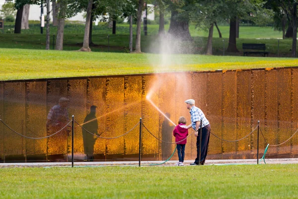 Hombre y niña lavando la pared en el monumento a Vietnam — Foto de Stock