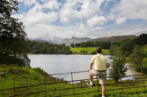 Wandelaar kijkt uit op loughrigg tarn in lake district — Stockfoto