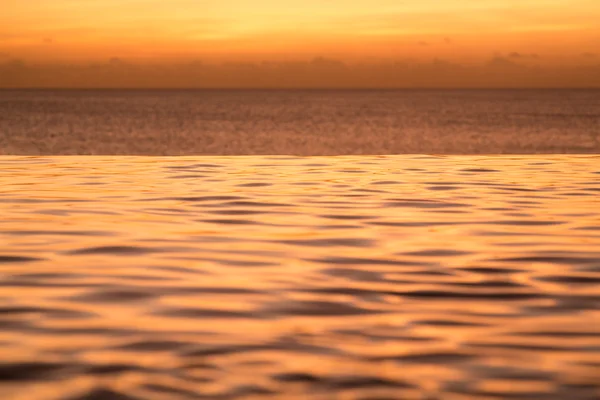 Piscina de borda infinita com mar embaixo do pôr do sol — Fotografia de Stock