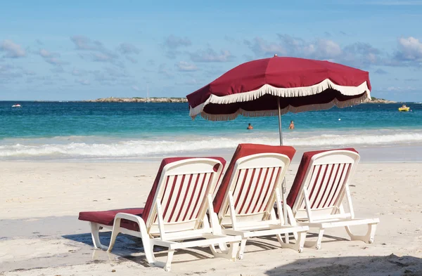 Drei Liegestühle und Sonnenschirm auf Sand — Stockfoto