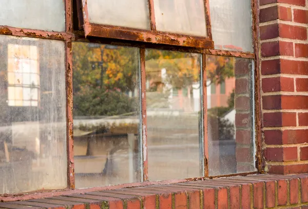 Vieille fenêtre rouillée dans l'entrepôt reflétant l'automne — Photo