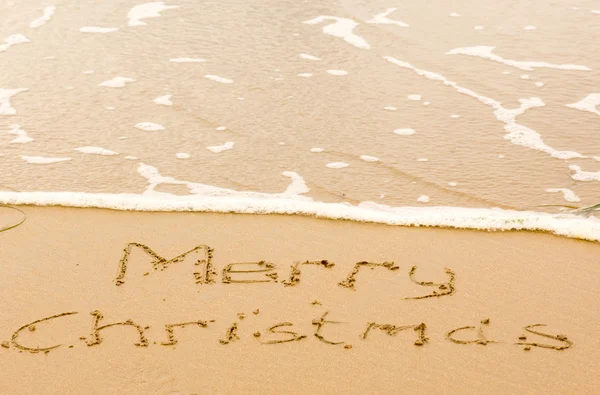 Merry Christmas written in sand on beach — Stock Photo, Image