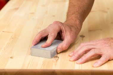 Mans hand on sanding block on pine wood clipart