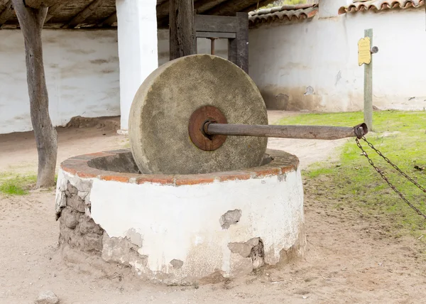 Old grinding wheel in garden of mission — Stock Photo, Image