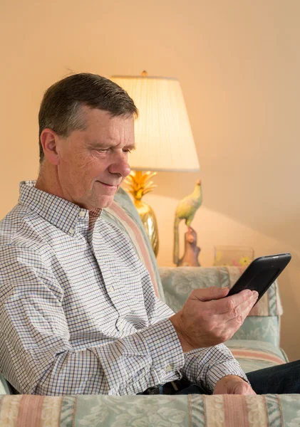 Starszy mężczyzna czytanie ebook na kanapie — Zdjęcie stockowe