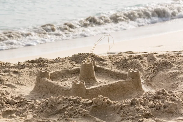 Childs sand castle on beach by ocean — Stock Photo, Image