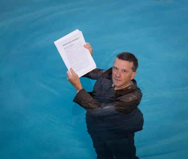 Senior hombre sosteniendo el documento del préstamo hipotecario en el agua —  Fotos de Stock