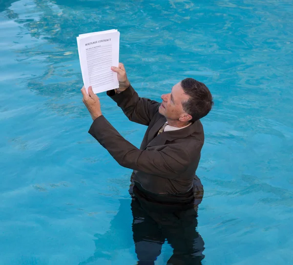 Senior man holding mortgage loan document in water — Stock Photo, Image