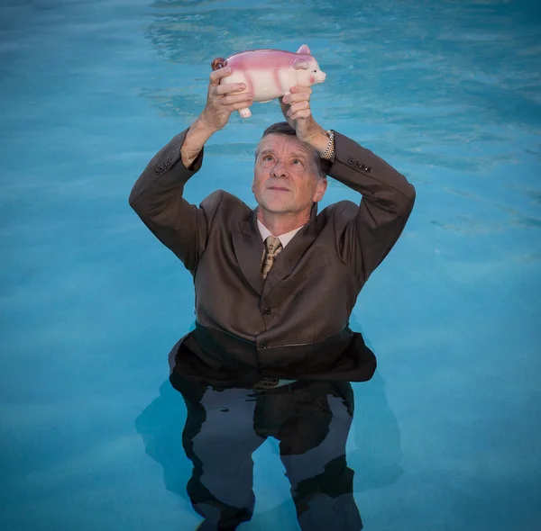 Uomo anziano che tiene salvadanaio sopra l'acqua — Foto Stock