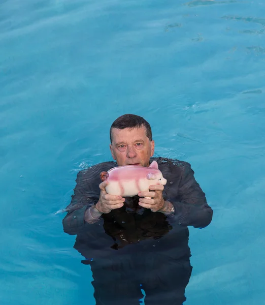 Uomo anziano che tiene salvadanaio sopra l'acqua — Foto Stock