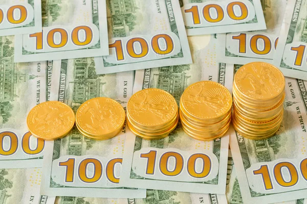 Gouden munten op nieuwe ontwerp 100 dollarbiljetten gestapeld — Stockfoto