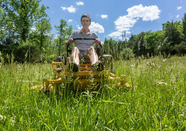 Homme âgé sur zéro tour tondeuse à gazon dans la prairie — Photo