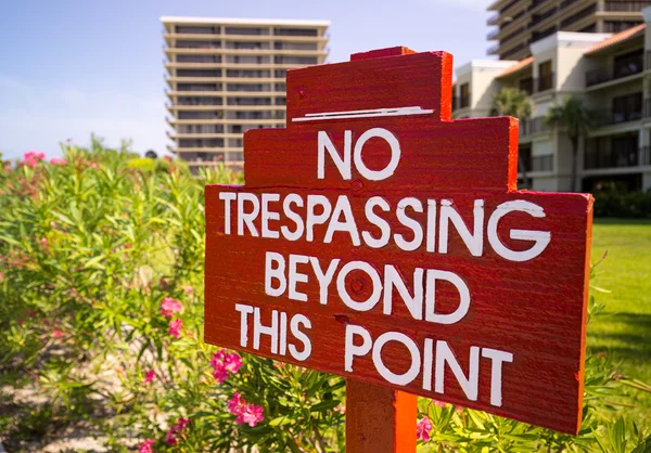 No Trespassing sign in red by flower gardens — Stock Photo, Image