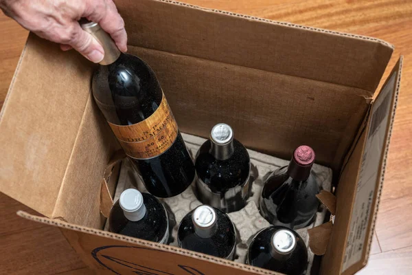 高级男子在家中分娩后检查一箱六瓶赤裸酒中的葡萄酒 — 图库照片