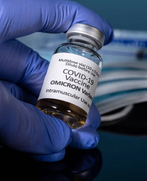 Закрыть бутылку новой вакцины Ковид-19 для варианта Омикрон с перчаткой — стоковое фото