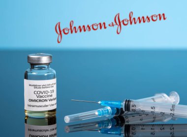 Omicron aşısı şişesinde Johnson ve Johnson 'ın arka planında şırınga var.