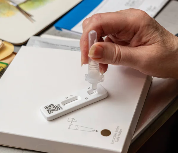 Self-test kit for Covid-19 with buffer solution being dripped onto test strip — Stockfoto