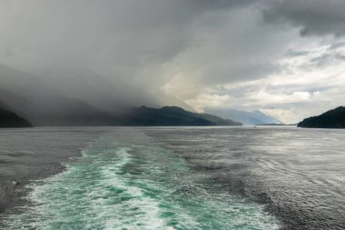 Cruise ship wake leads back up the inside passage on an Alaskan tour to rain storm