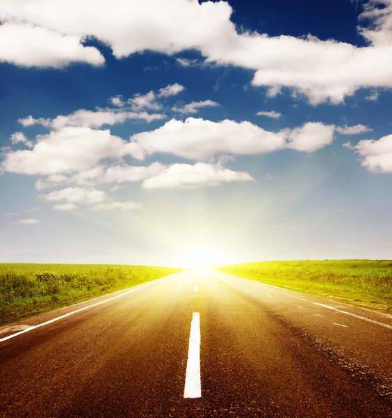 Асфальтовая дорога с облачным небом и солнечным светом — стоковое фото