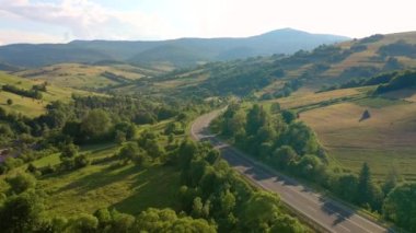 İnsansız hava aracı yeşil alp çayırlarından geçen yolun üzerinden uçuyor. 4k, İHA videosu ile çekilmiştir..