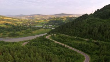 İnsansız hava aracı bir dağ geçidinden geçen dolambaçlı bir yolda uçuyor. Karpat Dağları, Ukrayna, Avrupa. Sinematik hava çekimi. Dünyanın güzelliğini keşfet. 4k, İHA videosu ile çekilmiştir..