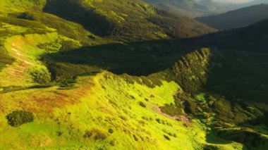 Güneşli bir günde kuşbakışı manzaralı yeşil bir dağ sırasının çekici manzarası. 4k, İHA videosu ile çekilmiştir..