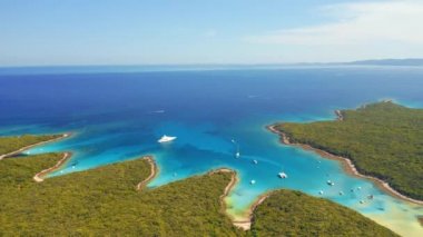 İHA güneşli bir günde gök mavisi körfezinde yelkenlilerle uçuyor. 4K 'da çekilmiş..