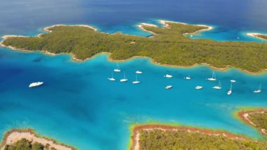 İHA güneşli bir günde gök mavisi körfezinde yelkenlilerle uçuyor. 4K 'da çekilmiş..