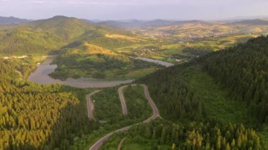 İnsansız hava aracı bir dağ geçidinden geçen dolambaçlı bir yolda uçuyor. Karpat Dağları, Ukrayna, Avrupa. Sinematik hava çekimi. Dünyanın güzelliğini keşfet. 4k, İHA videosu ile çekilmiştir..