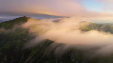 İnsansız hava aracı, tepenin üzerinden geçen sisin üzerinden uçuyor. 4k, İHA videosu ile çekilmiştir..