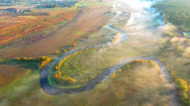 Yukardaki kıvrımlı nehir manzarası ve sis kuş bakışı düzlükten aşağı yuvarlanıyor. 4k, İHA videosu ile çekilmiştir..