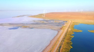 Rüzgar türbinleriyle tuzlu bir düzlükte uçan bir İHA 'dan ateş etmek. 4k 'lık bir videoda çekildi.