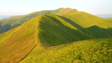 Güneşin aydınlattığı yeşil tepelerle sakin bir yaz günü. 4k, İHA videosu ile çekilmiştir..