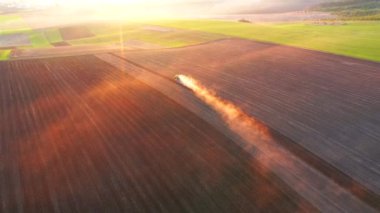 Traktörün arkasından bir toz bulutu yükseliyor ve bir kuşun gözünden toprağı sürüyor. 4k, İHA videosu ile çekilmiştir..