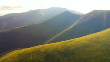 Güneşin aydınlattığı yeşil tepelerle donanımlı bir yaz günü. 4k, İHA videosu ile çekilmiştir..