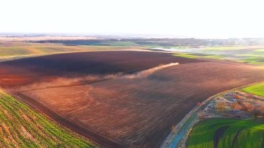 Endüstriyel bir traktör zemin tarlasını kuşbakışı sürüyor. 4k, İHA videosu ile çekilmiştir..