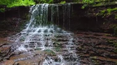 Bir kuadkopter, egzotik bir şelalenin üzerinde ağaçlık yeşil bir kanyonda uçar. UHD 4k video ile çekildi.