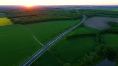 İnsansız hava aracı otoban üzerinde uçuyor ve akşam yeşil alanlar üzerinde uçuyor. UHD 4k video ile çekildi.
