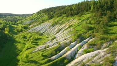 Tebeşir tepeleri ve yeşil ormanın üzerinde uçan bir helikopter. UHD 4k video ile çekildi.