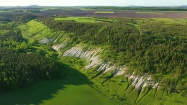Tebeşir tepeleri ve yeşil ormanın üzerinde uçan bir helikopter. UHD 4k video ile çekildi.
