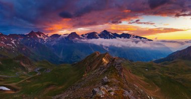 Alacakaranlıkta gün ışığıyla parlayan tepelerin muhteşem manzarası. Dramatik ve resimli bir sabah sahnesi. Ünlü Grossglockner High Alpine Yolu, Avusturya. Avrupa. Sanatsal resim. Güzellik dünyası.