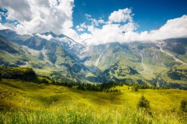 Güneş ışığıyla parlayan yeşil tepelerin harika manzarası. Dramatik ve resimli bir sabah sahnesi. Avusturya 'nın ünlü tatil beldesi Grossglockner High Alpine Yolu. Avrupa. Sanatsal resim. Güzellik dünyası. 