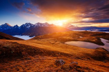 Koruldi Gölü 'nün muhteşem gölünün eteklerinde bulutlu kırmızı gökyüzü. Ushba. Dramatik bir sahne. Svaneti, Mestia, Gürcistan, Avrupa 'da ünlü bir yer. Yüksek Kafkasya sırtı. Sıcak tonlama etkisi. Güzellik dünyası.
