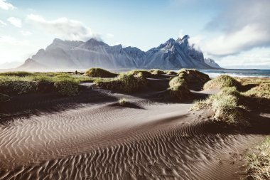 Güneş ışığıyla parlayan alışılmadık tepeler. Dramatik ve muhteşem bir sahne. Turist eğlencesi. Stoksnes Burnu, Vestrahorn (Mt. Batman), İzlanda, Avrupa. Bağbozumu etkisi. Instagram filtresi. Güzellik dünyası.