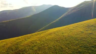 Güneşin aydınlattığı yeşil tepelerle sakin bir yaz günü. 4k, İHA videosu ile çekilmiştir..