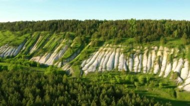 Beyaz kumlu tepeler ve yeşil ormanlar üzerinde uçan drone. UHD 4k video ile çekildi.