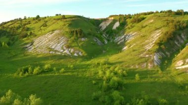 Güneşli bir günde kuşbakışı manzaralı, yeşil tepeleri olan görkemli bir kırsal. UHD 4k video ile çekildi.
