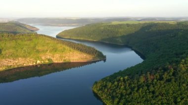 Yeşil tepelerden akan kıvrımlı nehrin panoramik manzarası kuş bakışı. UHD 4k video ile çekildi.